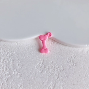 Detailed view of a shiny pink bone-shaped alloy pendant with hole for DIY jewelry design