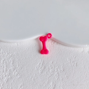 Close-up of a bright pink bone-shaped pendant accessory for DIY crafts and jewelry