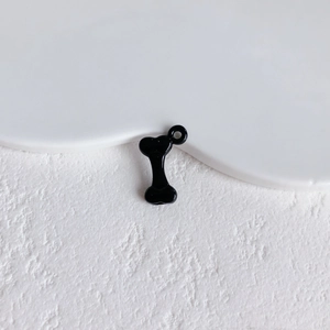 Macro detail of bone shaped black enamel alloy pendant with integrated hanging loop