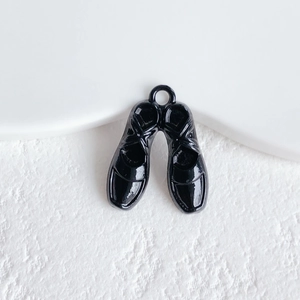 Macro shot of black enamel twin shoe charms with metallic hooks for DIY jewelry making