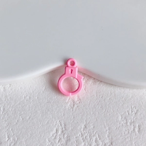 Close-up of pink handcuff-shaped charm accessory for DIY jewelry and crafts