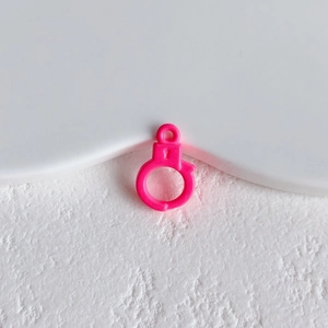 Close-up of a rose pink handcuff shaped DIY charm with a small loop for jewelry making
