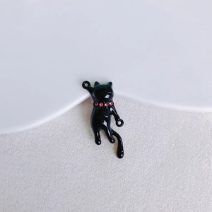 Dettaglio macro di un ciondolo a gatto in smalto nero con strass rosa per gioielli DIY