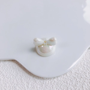 Macro shot of white acrylic bow bead with iridescent pearl finish for DIY jewelry craft