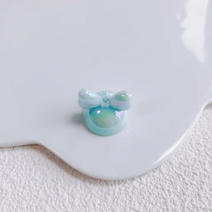 Close-up of a pearlescent light blue acrylic bow charm for DIY jewelry and phone cases
