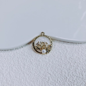Makroaufnahme von Korallenanhänger mit lila Strasssteinen und weißer Perle in Gold