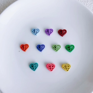 Macro detail of multi-color heart-shaped alloy beads with hollow butterfly engravings