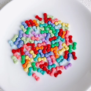 Bunte Makronen-Legierungsperlen in Schleifenform für DIY-Schmuck auf einem Teller