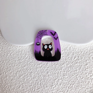 Dettaglio macro di un ciondolo di Halloween in acrilico viola con gatto nero e ragnatela