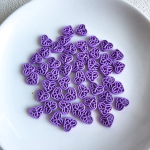 Close-up of purple hollow heart beads with butterfly patterns for DIY jewelry making