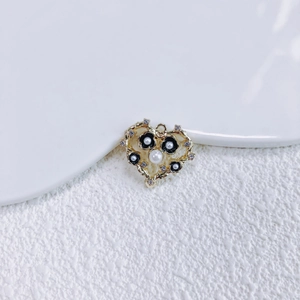 Makro-Detail von herzförmigem Goldanhänger mit schwarzen Blumen und Perlen für DIY-Schmuck