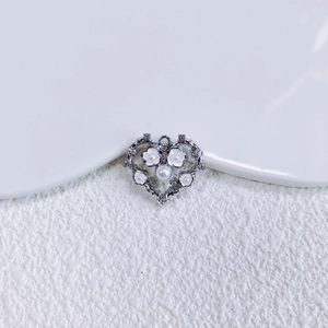 Makroaufnahme von Herzanhänger aus Silber mit Blumen-Perlen-Inlay und Vintage-Design