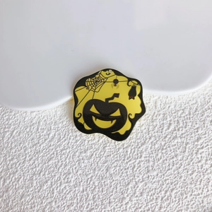 Dettaglio macro di un ciondolo acrilico di Halloween con ragnatela e zucca su vassoio