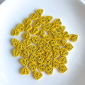 Macro shot of lemon yellow hollow heart charms with ornate scrollwork for DIY jewelry