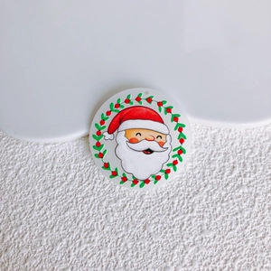 Dettaglio di un ciondolo tondo in acrilico con Babbo Natale dipinto a mano e ghirlanda
