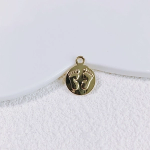 Nahaufnahme eines goldenen Anhängers mit Baby-Fußabdruck für DIY-Halsketten und Armbänder