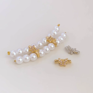 Detalle de cuenta de mariposa dorada con circonitas rosas y tira de perlas blancas para joyas DIY