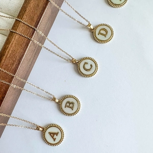 Detailed view of gold plated alphabet pendants featuring natural shell inlay and letters A to D