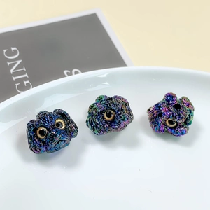 Macro detail of three colorful iridescent puppy-shaped DIY metal beads with metallic finish