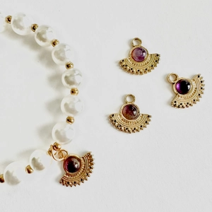 Elegant pearl bracelet with fan-shaped gold pendant and purple stone on white background