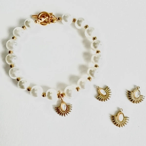 Lustrous pearl bead bracelet with sunburst pendant and toggle clasp in gold-plated steel