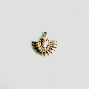 Macro detail of vintage gold fan-shaped pendant with embossed stone and sunburst spikes