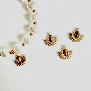 Detail of gold fan-shaped pendants with amber stones and white pearl bead jewelry
