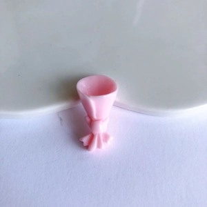 Macro detail of a mini pink resin flower bouquet charm with bow for DIY crafts