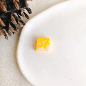 Détail macro d'une perle de Noël carrée jaune avec motifs église d'hiver et flocons de neige
