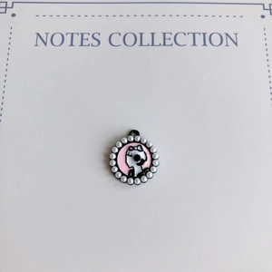 Détail du pendentif rond avec incrustation de perles et silhouette noire en émail