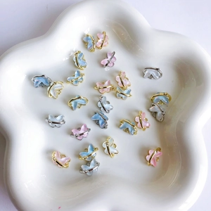 Pendentifs papillon en résine avec cadres métalliques sur plateau floral blanc