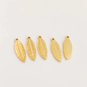 Macro detail of 316L gold leaf pendants with engraved tribal textures and small hanging holes