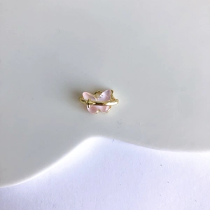 Détail macro du pendentif papillon en résine rose avec anneau planétaire doré et bélière