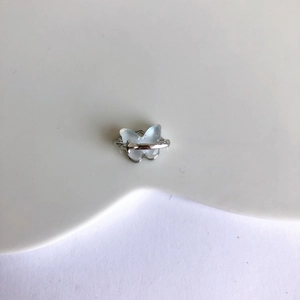 Détail macro d'une bague papillon argentée avec ailes en résine bleu clair et croix