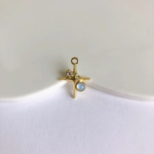 Detailed view of a gold cross pendant with light blue moonstone and zircon for DIY jewelry