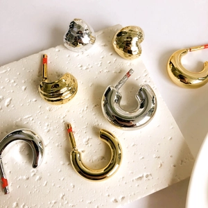 Close-up of assorted vintage acrylic and metal C-shape hoop earrings on stone