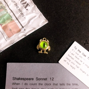 Close-up of gold alloy monster charm with green cat eye stone for DIY jewelry
