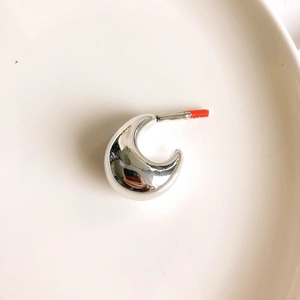 Detailed close-up of chunky silver C-shape earrings with high-polish metallic finish