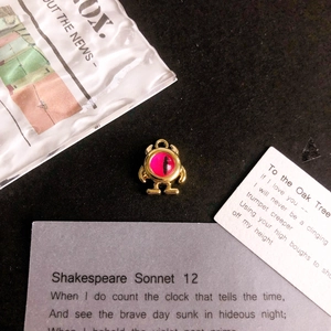 Macro shot of gold-tone monster pendant with magenta eye detail for DIY jewelry