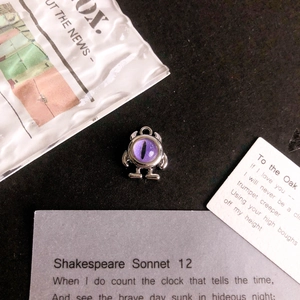 Detailed view of a purple monster eye charm for DIY jewelry on vintage script cards