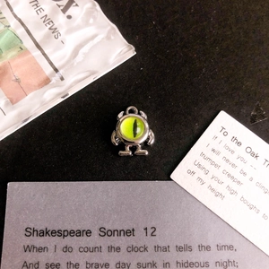 Macro shot of silver monster pendant with green eye detail on a vintage background