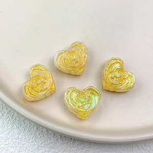 Macro detail of heart-shaped beads with rose relief pattern and iridescent aurora coating