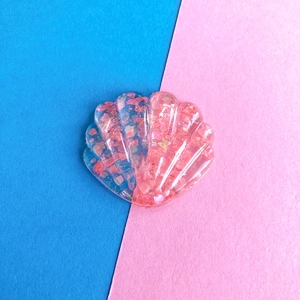 Dettaglio di un accessorio per capelli in resina a forma di conchiglia con glitter rosa