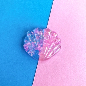 Dettaglio di accessorio per capelli a conchiglia in resina rosa e viola con brillantini