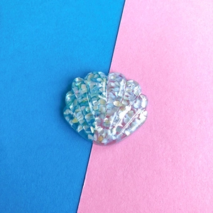 Dettaglio di ciondolo a conchiglia in resina con glitter per accessori capelli oceano