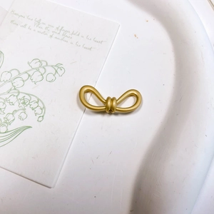 Vue macro détaillée d'un accessoire en métal doré mat en forme de nœud sur une carte