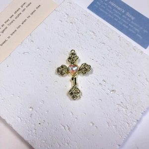 Detailed shot of vintage gold cross pendant with rose relief and iridescent heart stone