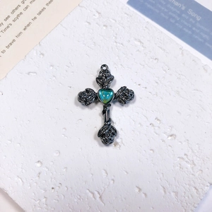 Macro detail of gothic cross pendant with rose relief and heart-shaped opal stone