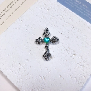 Detailed macro view of vintage silver cross pendant with heart stone and rose details