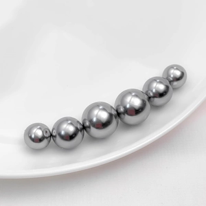 Various sizes of polished grey acrylic pearls with high metallic shine on a white plate